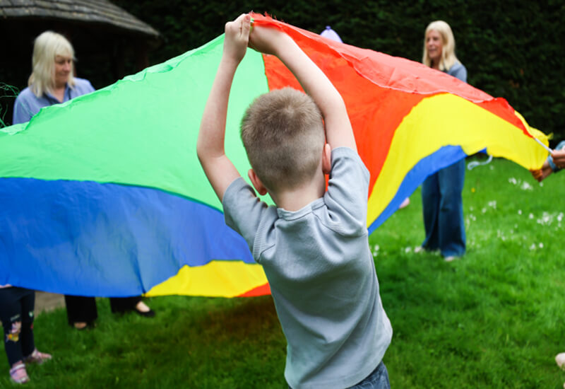 children and adults playing with colourful parachute