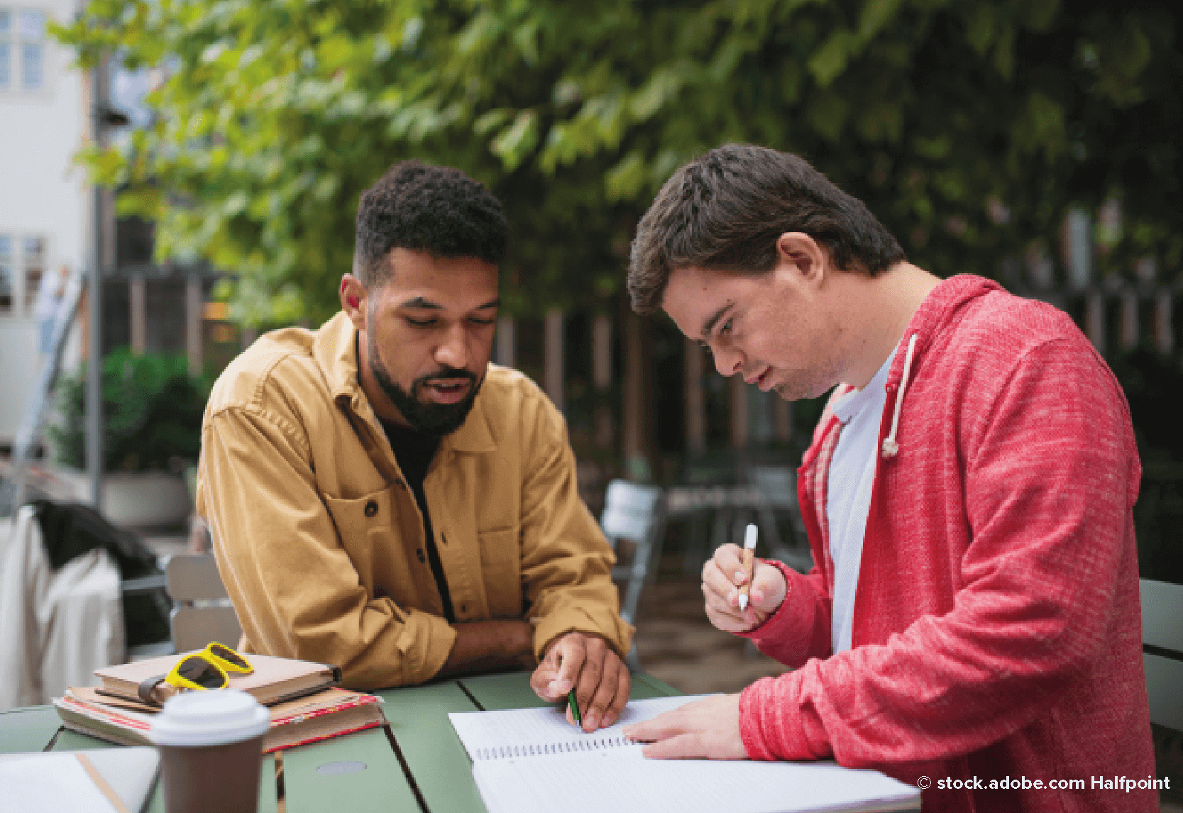 A man in a yellow jacket helping a boy in a red hoody